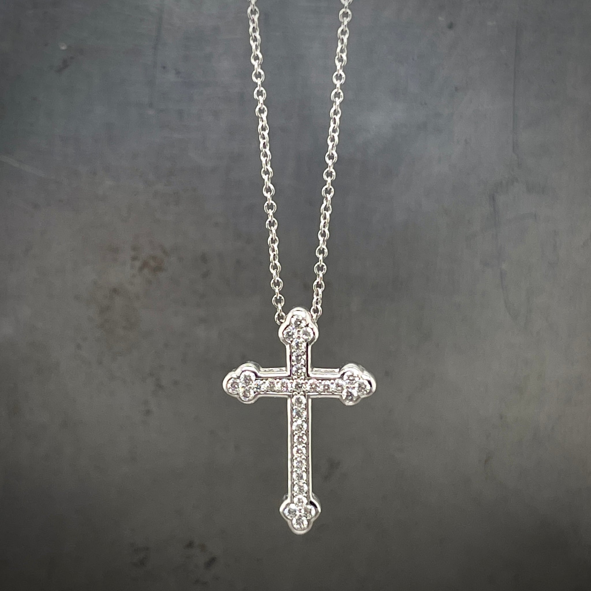 Close up view of diamond cross hanging on gray background.