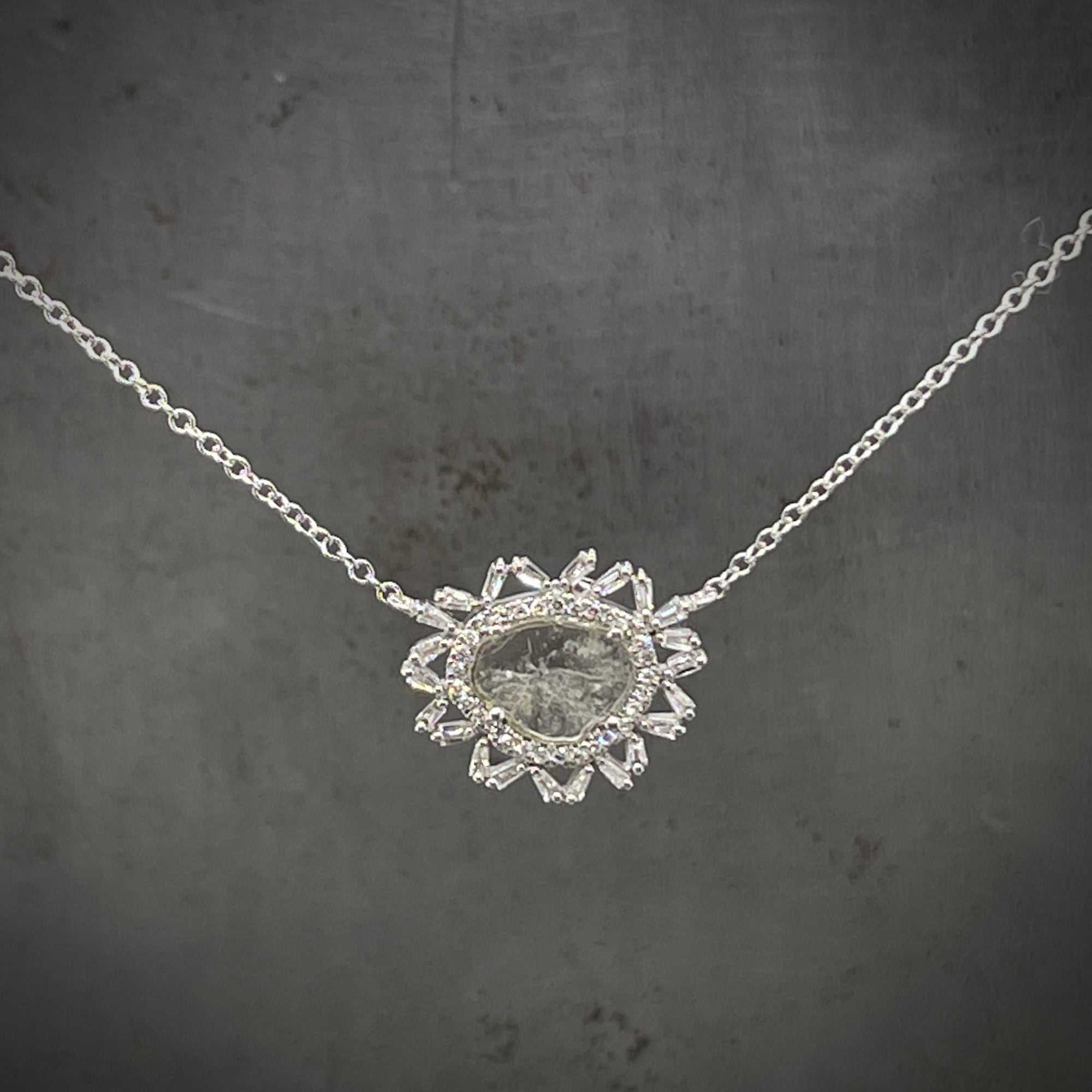 Close up view of white gold diamond slice halo necklace hanging.