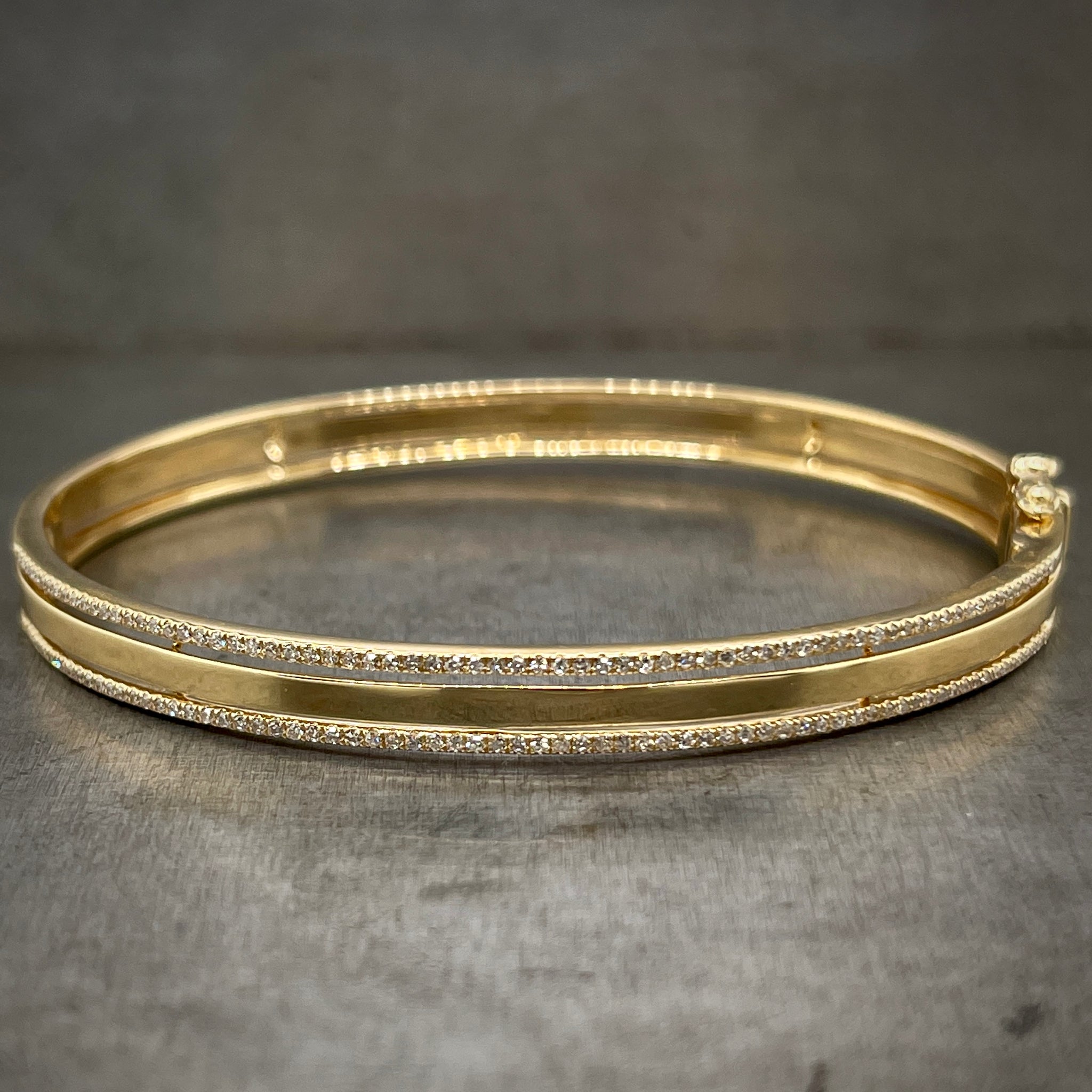 Full view of yellow gold and diamond bangle laying down.