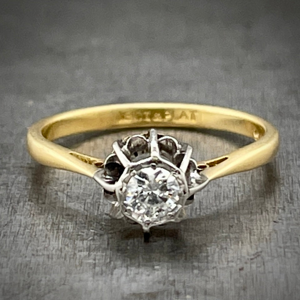 Full view of Antique Round Brilliant Engagement Ring laying down. Here you see the round diamond set in a floral-like platinum head that lays on an 18 karat yellow gold band.