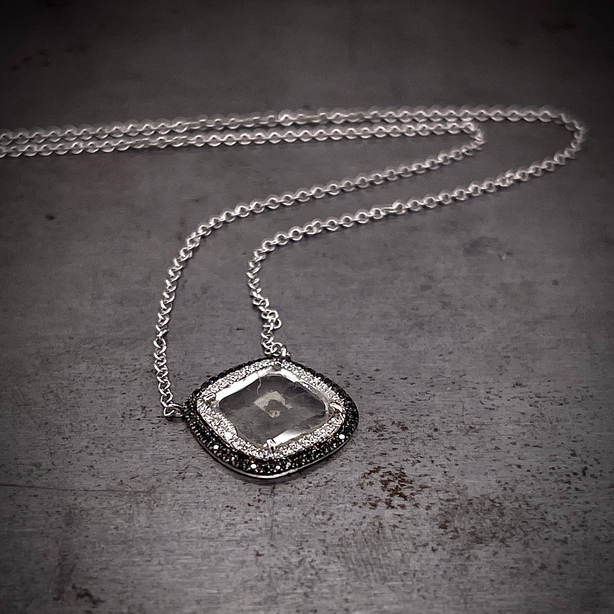 Full view of diamond slice and black diamond necklace laying down with its curb chain snaking through the image.
