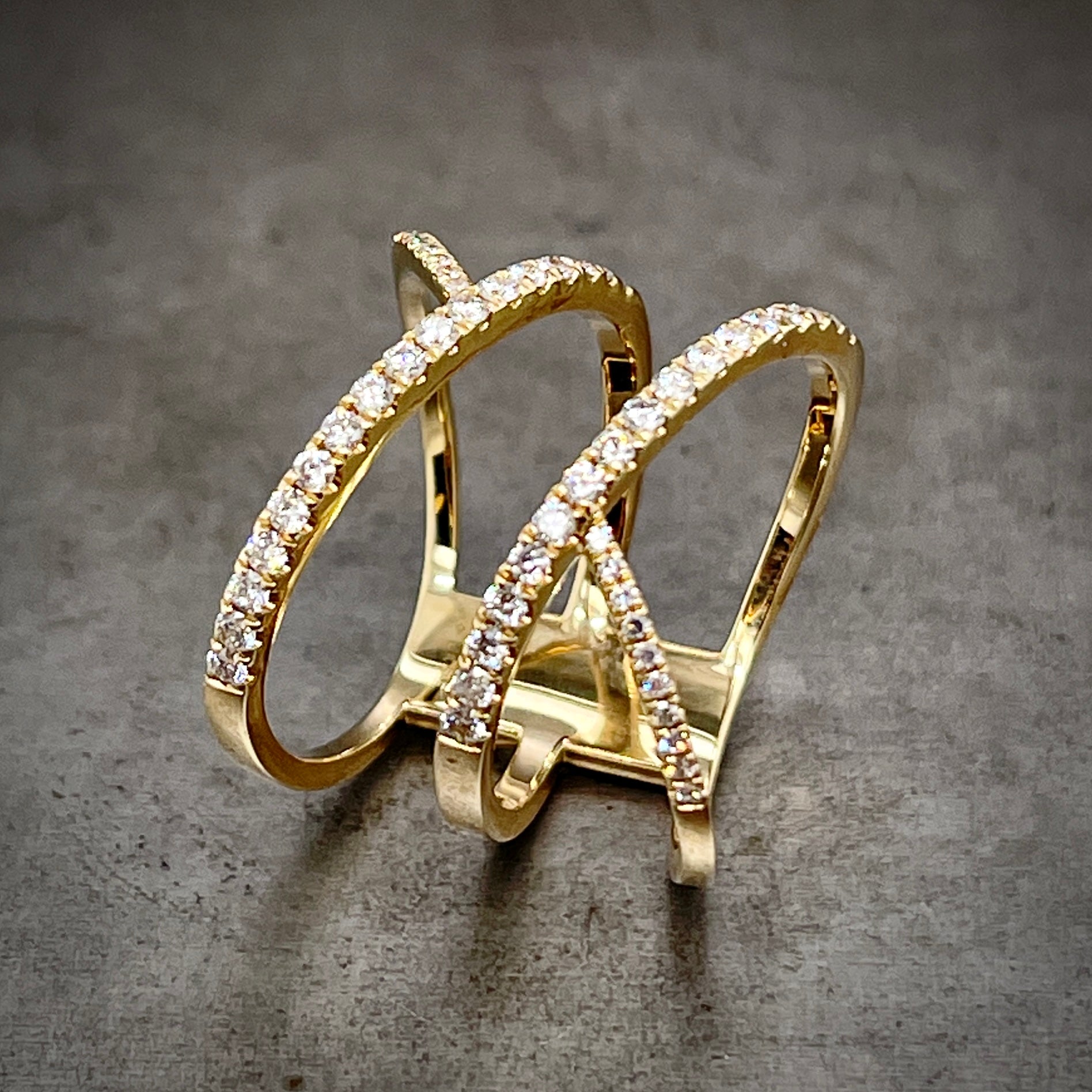 Angled aerial view of three in one diamond ring laying down. Here you can see the diamonds only go as far as the shoulders of the ring. Also the connection in the back of the ring is a big rectangle of yellow gold.