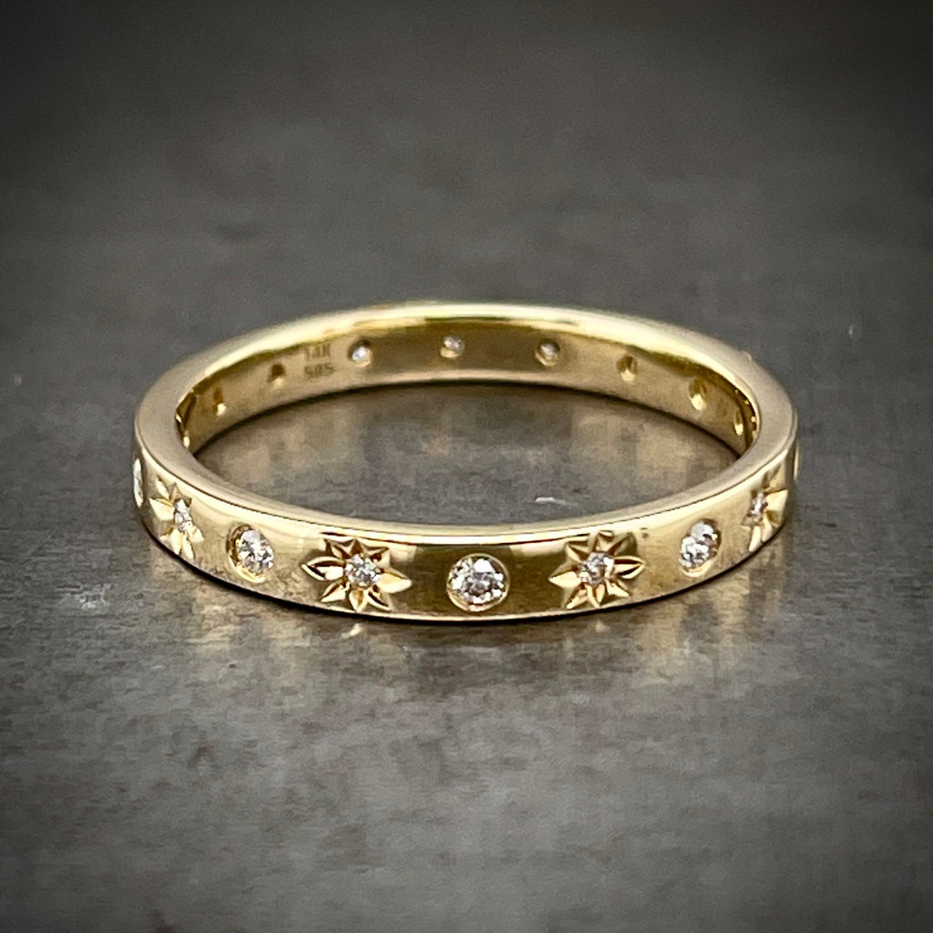 Full frontal view of diamond star ring. This band is rectangular and features a pattern of a flush set round brilliant diamond and then a round brilliant diamond set with a star etching behind it.