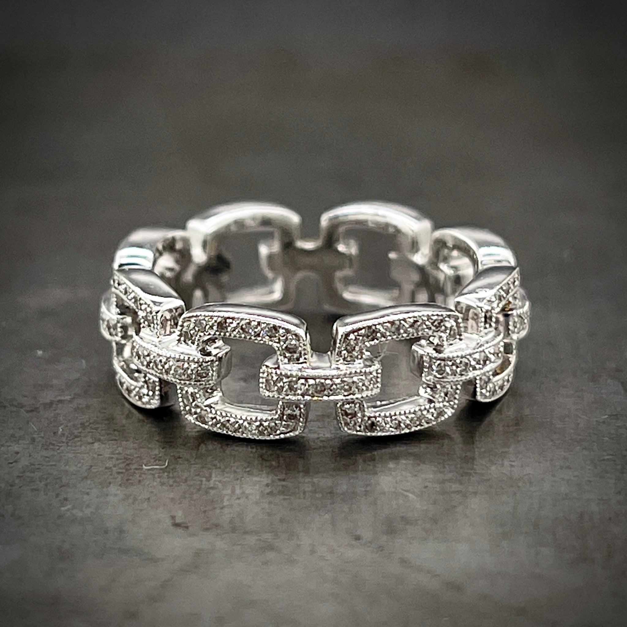 Full view of white gold and diamond chain ring laying down.