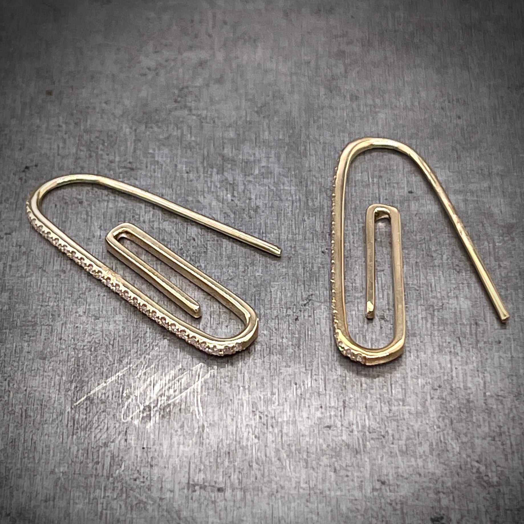 Full view of both paperclip earrings laying down. Here you can see the diamonds only travel on the front of the most forward layer of the paperclip.