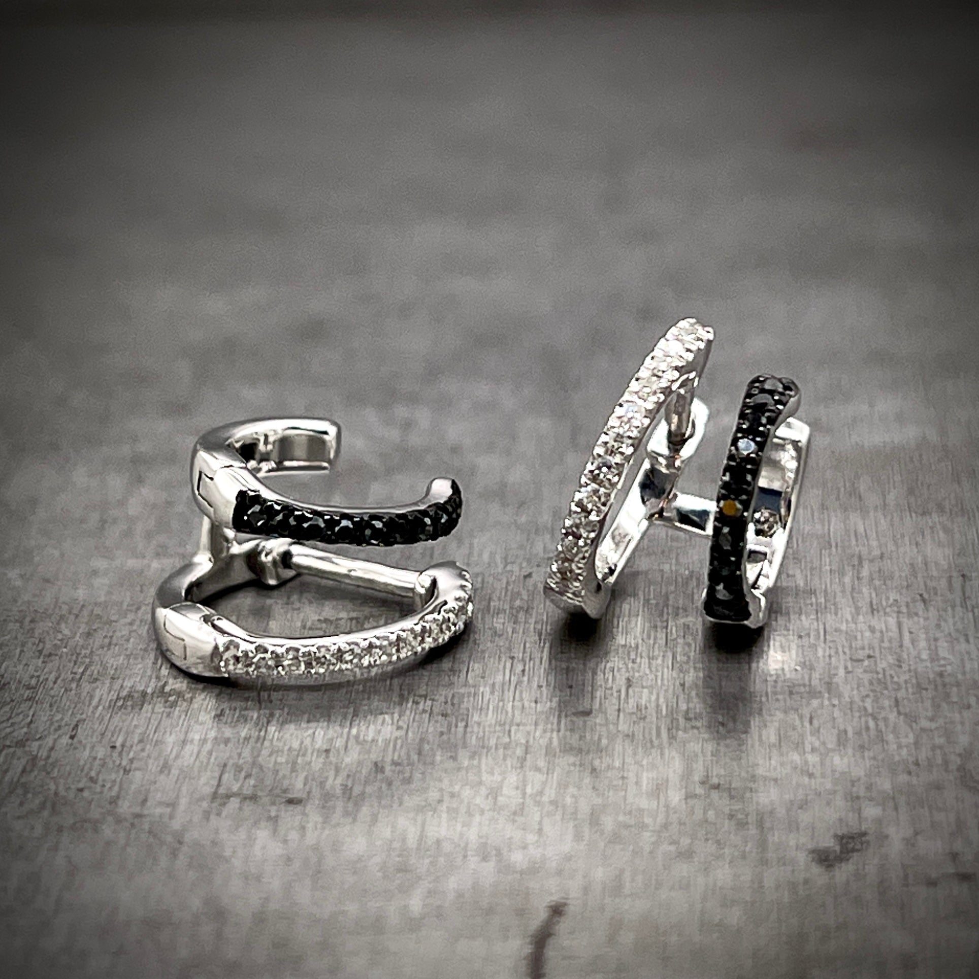 Full view of one hoop standing on the right and the other laying on its side on the left. In the left hoop, you can better see the single post that is attchted to the round brilliant diamond hoop.