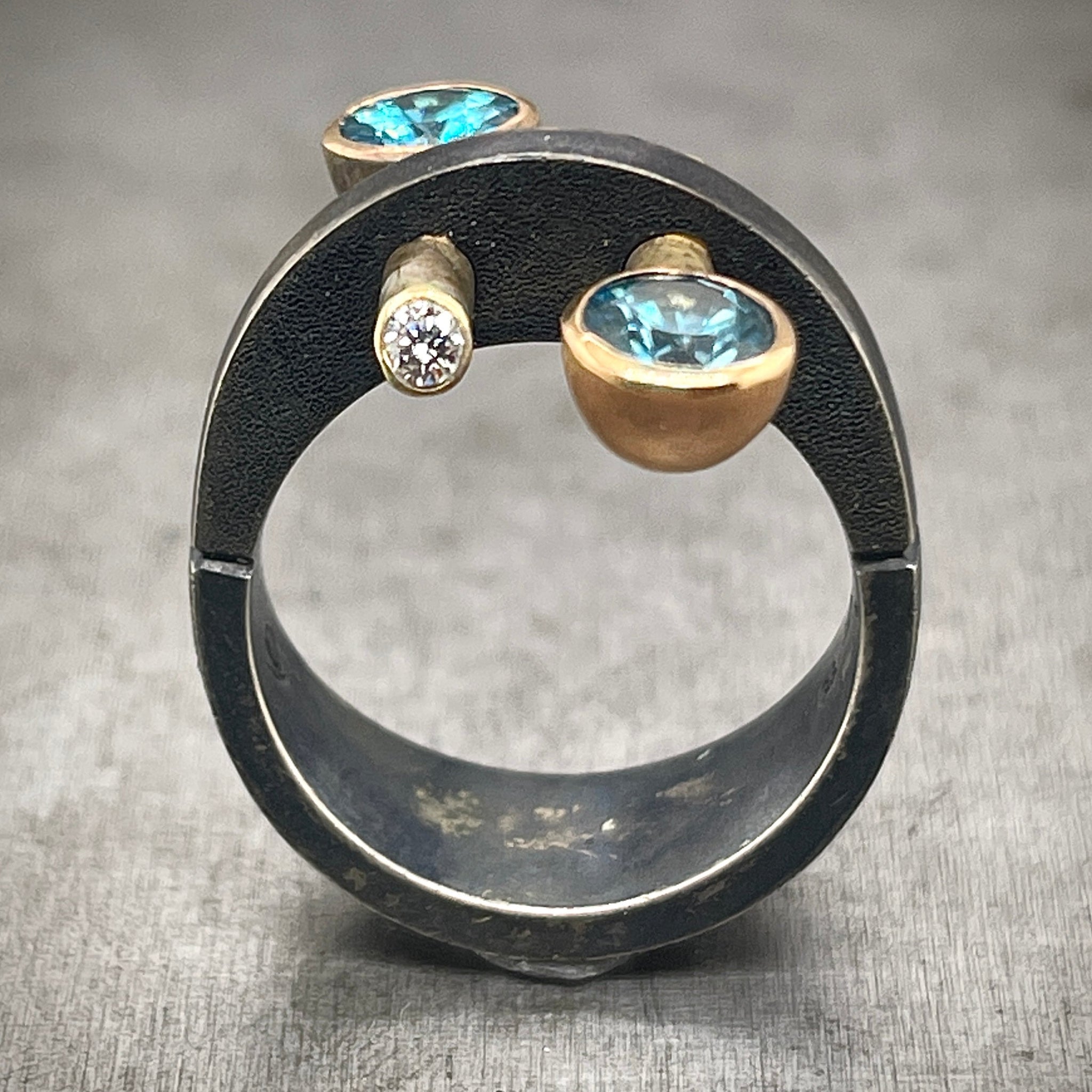 Oxidized Sterling Silver and Gold Ring, with Blue Zircons and Diamonds.. This image is a frontal view.