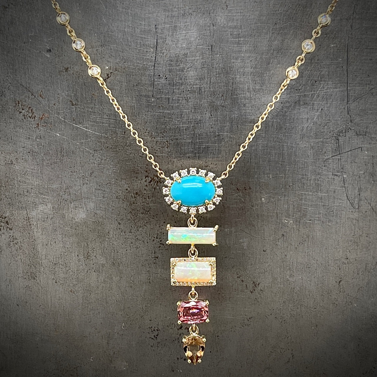 Front view of 14k yellow gold necklace presents a tapered sequence of colored gemstones, highlighted by diamond accents