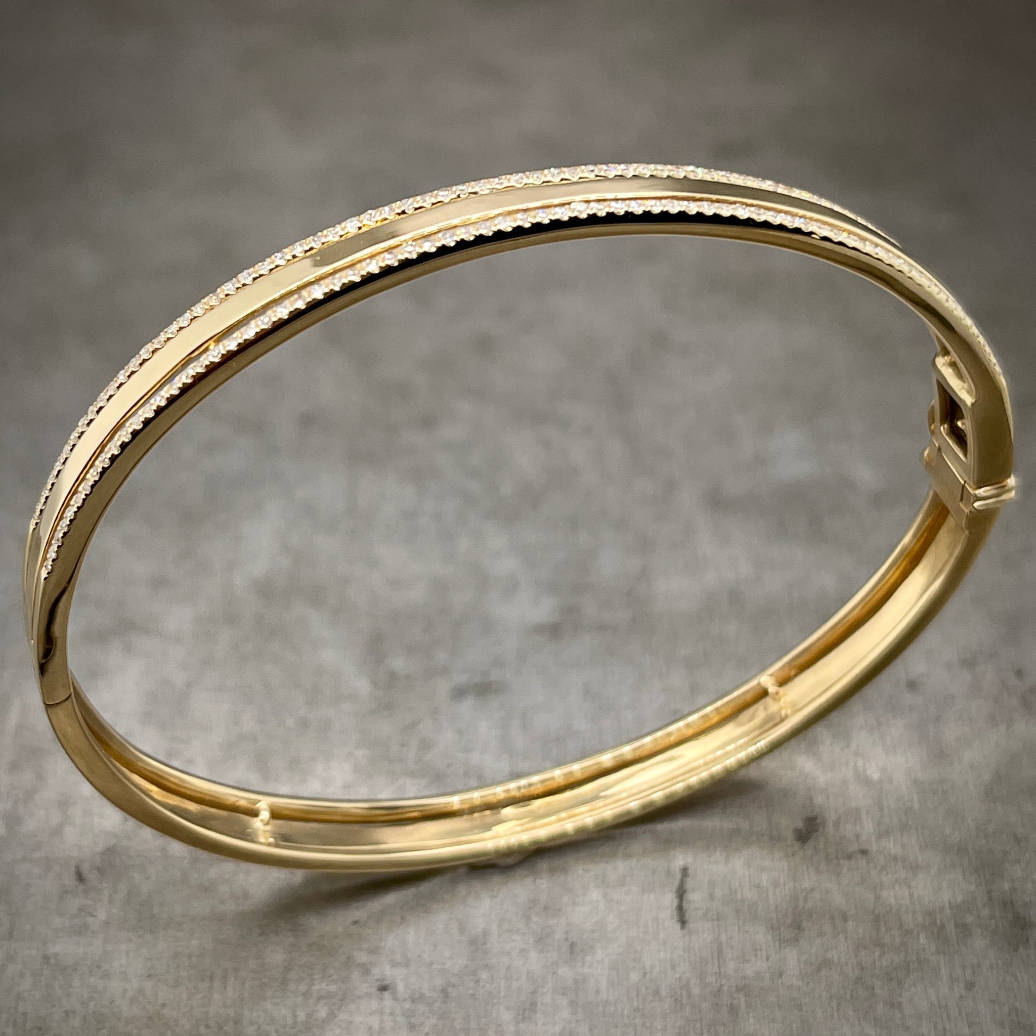 Full view of yellow gold and diamond bangle standing up.