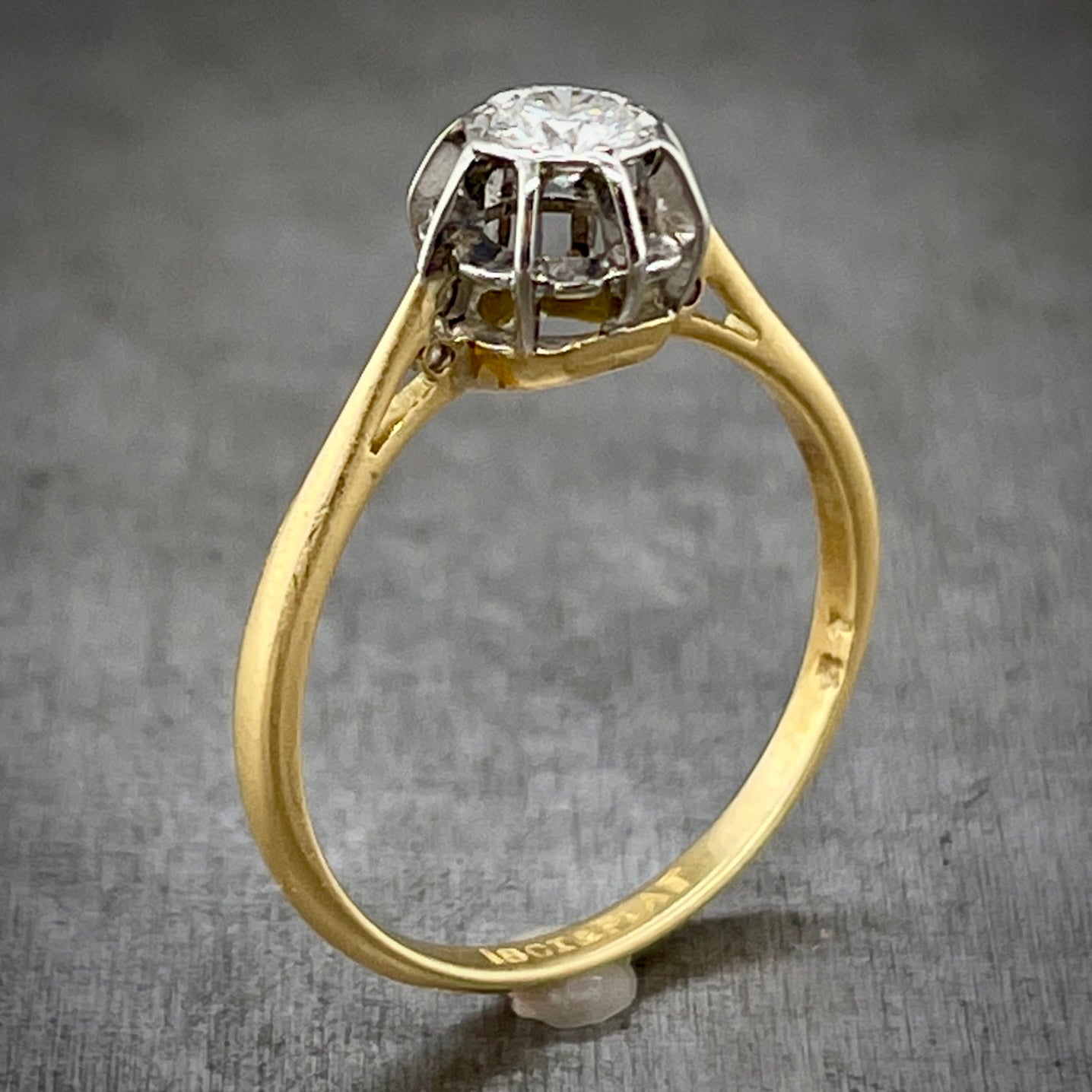 Angled aerial view of antique round brilliant engagement ring. Here you can better see the platinum head of the ring and that it look like a cage with bars going vertically and one horizontal bar that goes throughout all the head.