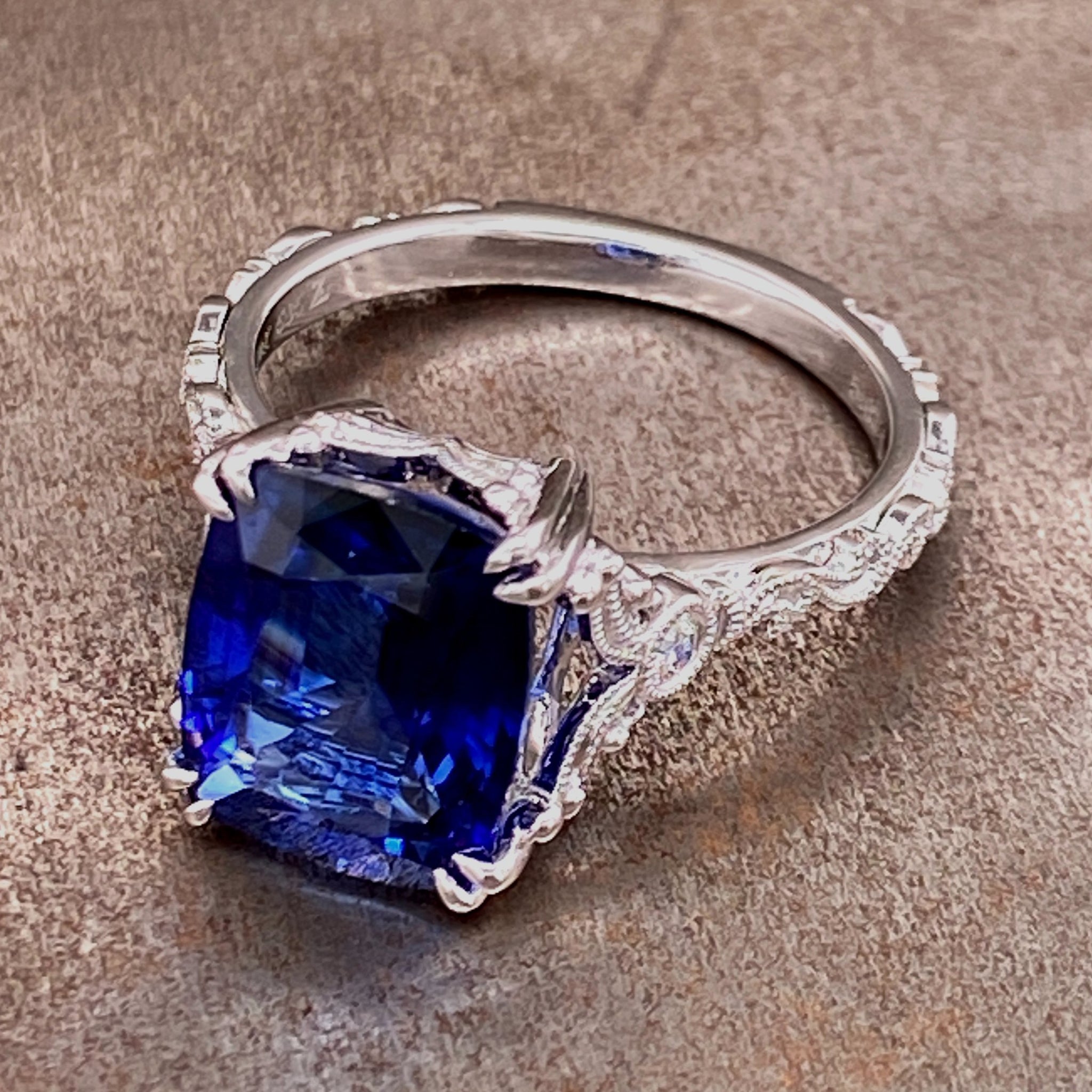Angled view of sapphire and 14 karat white gold ring laying down.