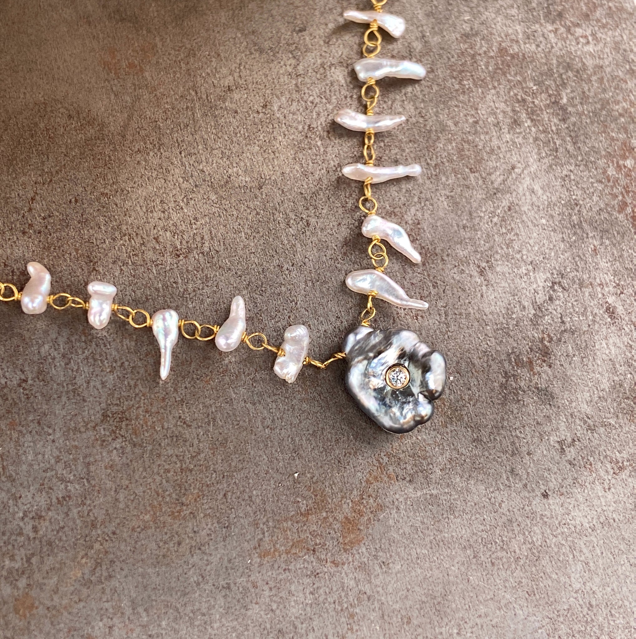 Close up view of keshi pearl and diamond necklace laying down.