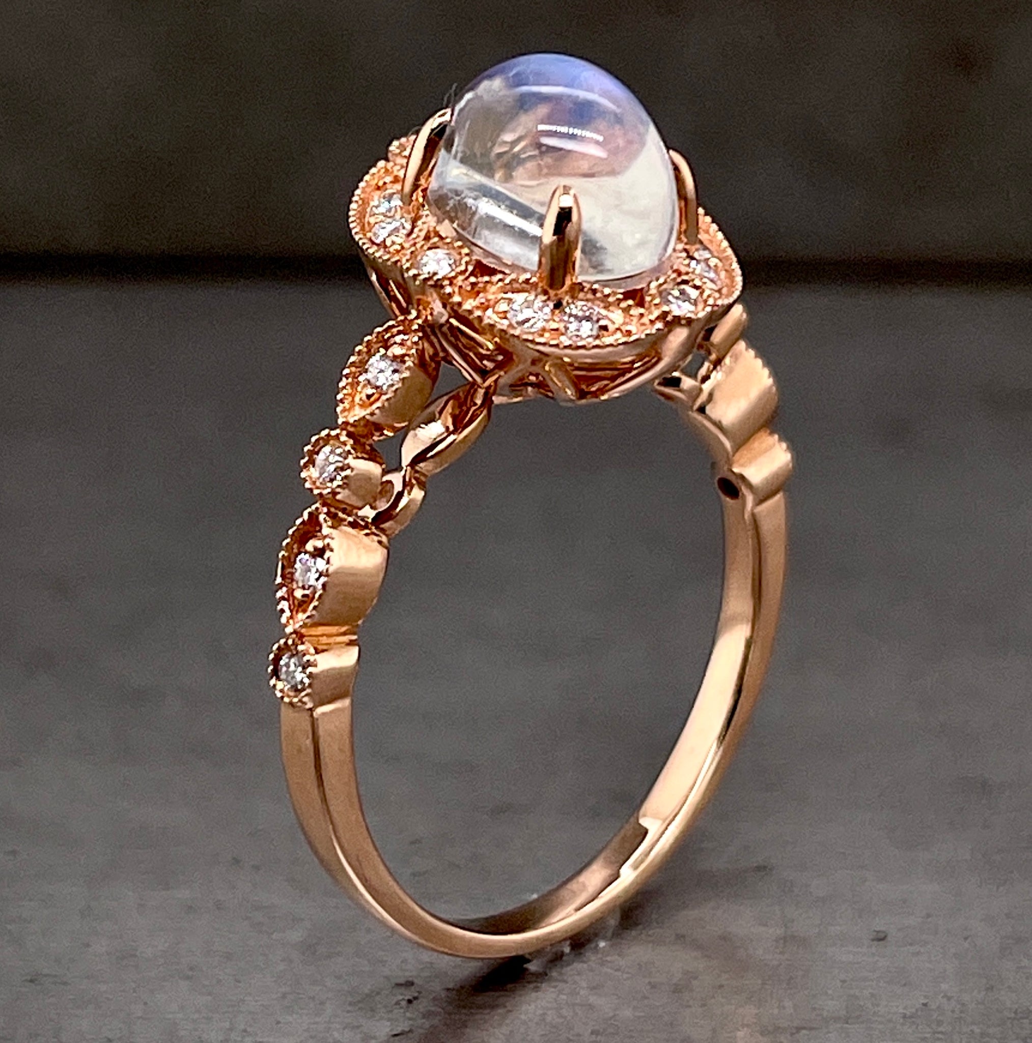 Angled side view of rose gold moonstone ring standing up. Here you can start to see an intricate design within the underside of the head setting of the moonstone.
