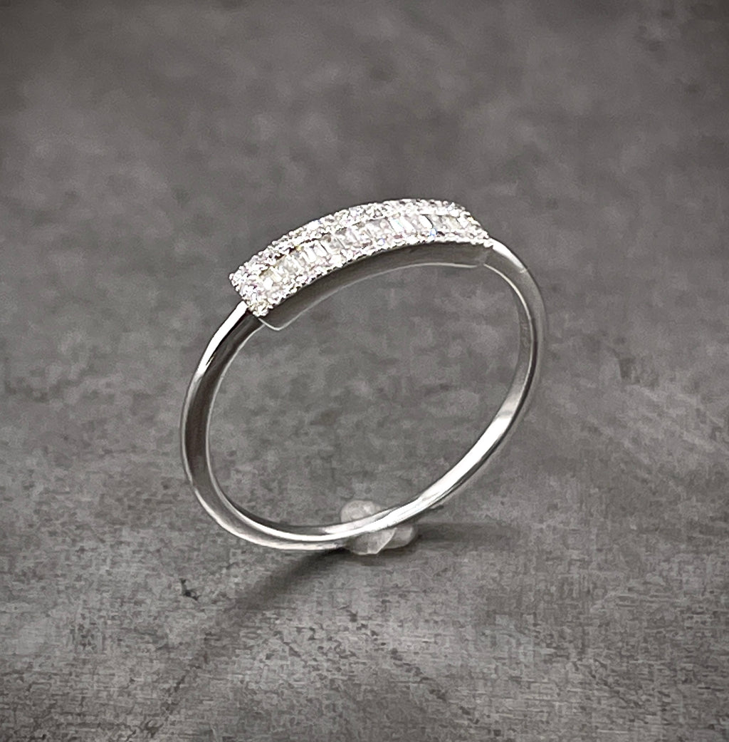 Aerial view of white gold diamond band. On the top of the ring is a thicker band that features baguette diamonds in the middle and a halo of round brilliant surrounding it.