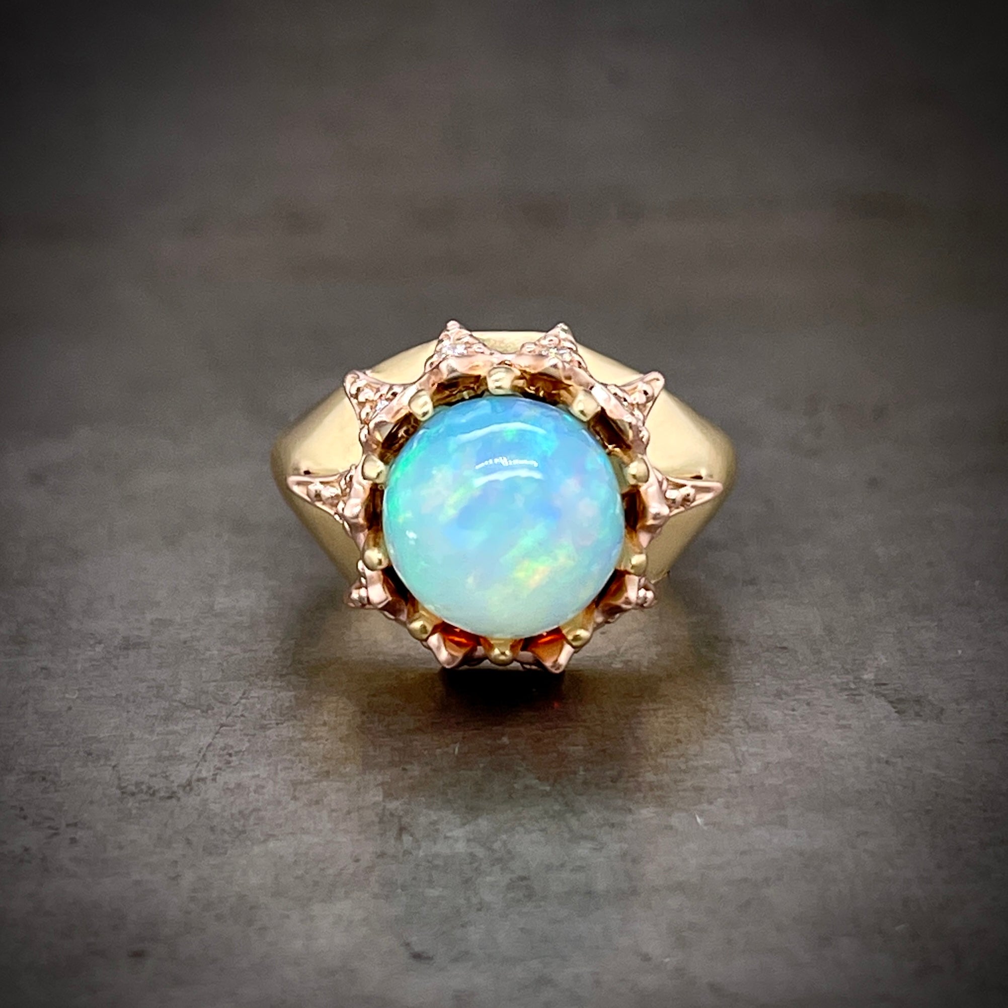 Aerial view of opal ring laying down. Here you can see the round opal and then the claw prongs that encompasses its entirety.