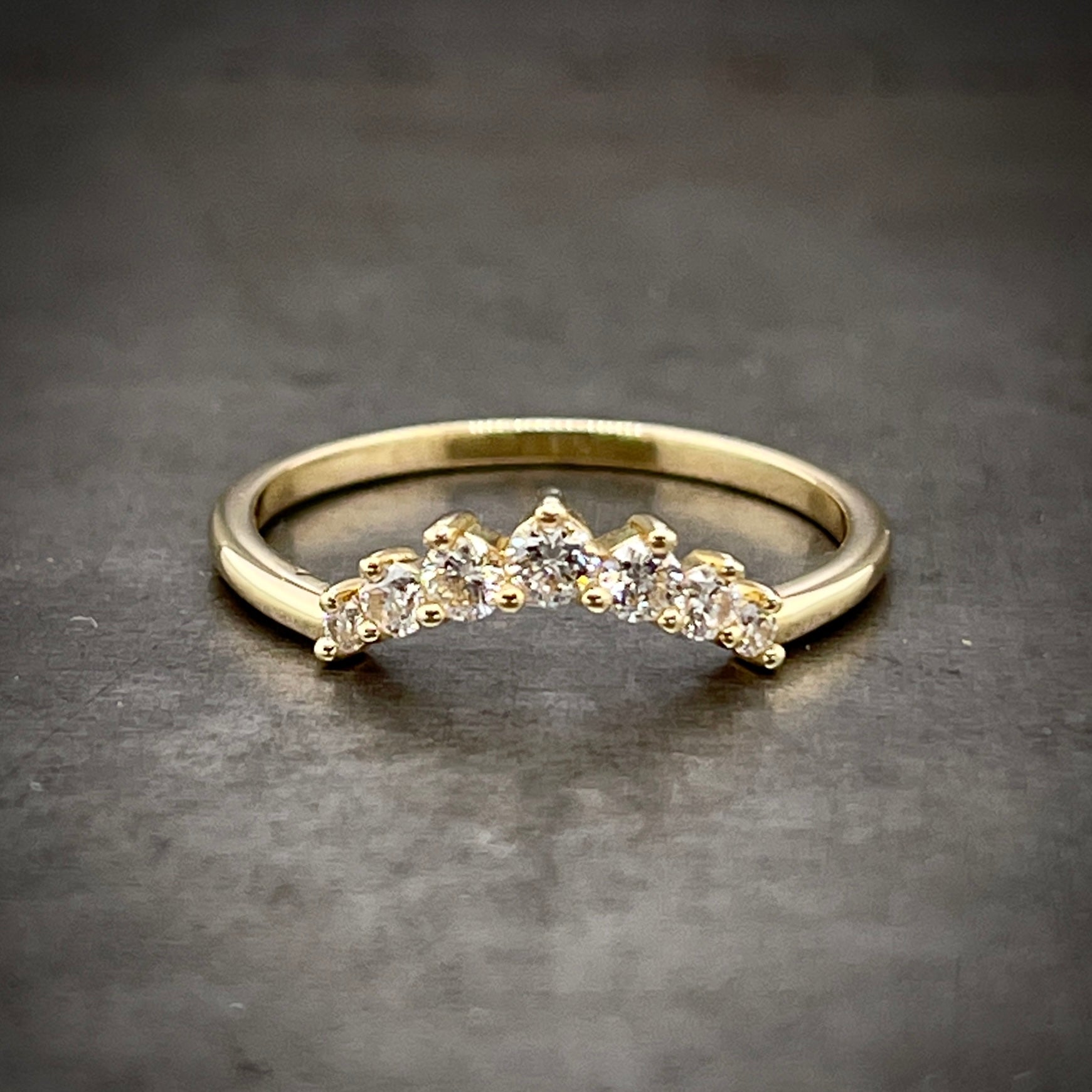Frontal vie of diamond tiara crown. This ring features seven diamond that create the shape of the curve of a tiara and decrease in size the further down it goes. Lays on a gold band.