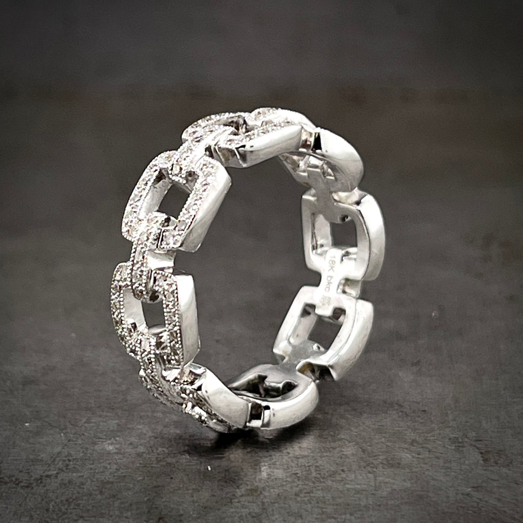 Angled view of white gold and diamond chain ring standing up. This ring looks like it is made out of cable chain. Covering the surface is a layer of round brilliant diamonds.