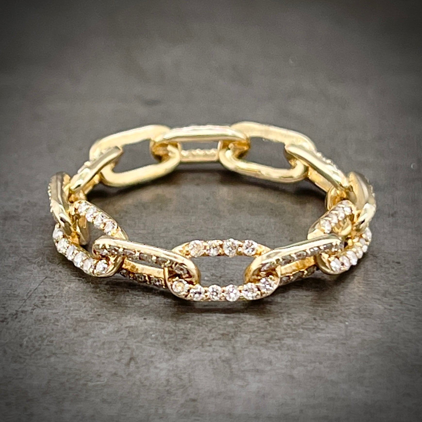 Full view of diamond yellow gold chain ring laying down.
