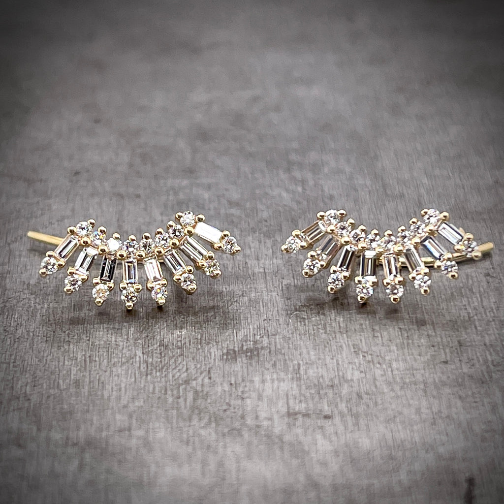 Frontal view of floral diamond ear climbers. These earrings feature a curved silhouette with the first layer being round brilliant diamonds, the second being baguette diamonds and the third being round brilliant diamonds. Each layer fans out more creating the perfect curvature for sitting on your ear.