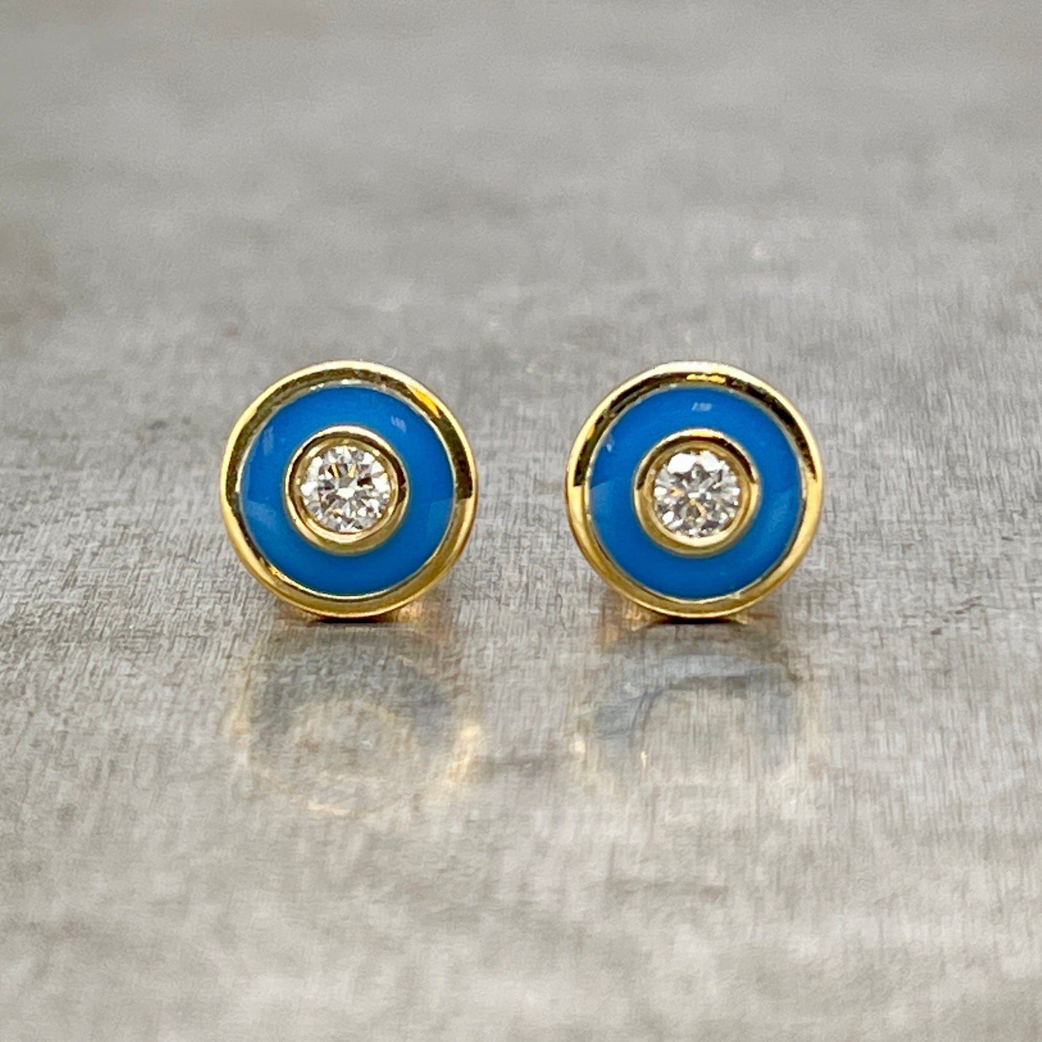 Frontal image of diamond and turquoise enamel studs. A bezel set round diamond is set in the center with a layer of turquoise enamel and then a thin layer of yellow gold.