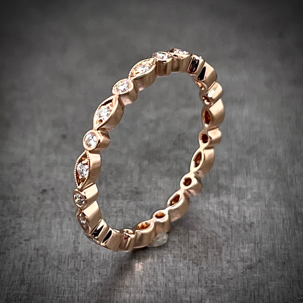 Aerial view of marquise and round eternity band. Made from rose gold, this band features a repetition of circle and marquise shapes, with a round diamond set in the center of each.