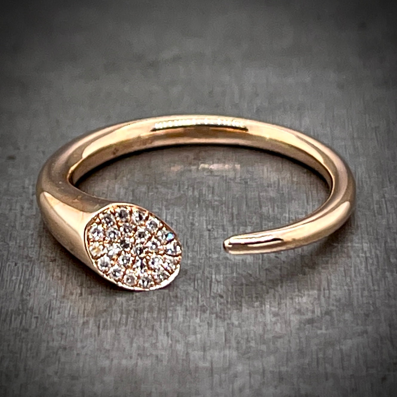 Full view of abstract rose gold and diamond ring laying down.
