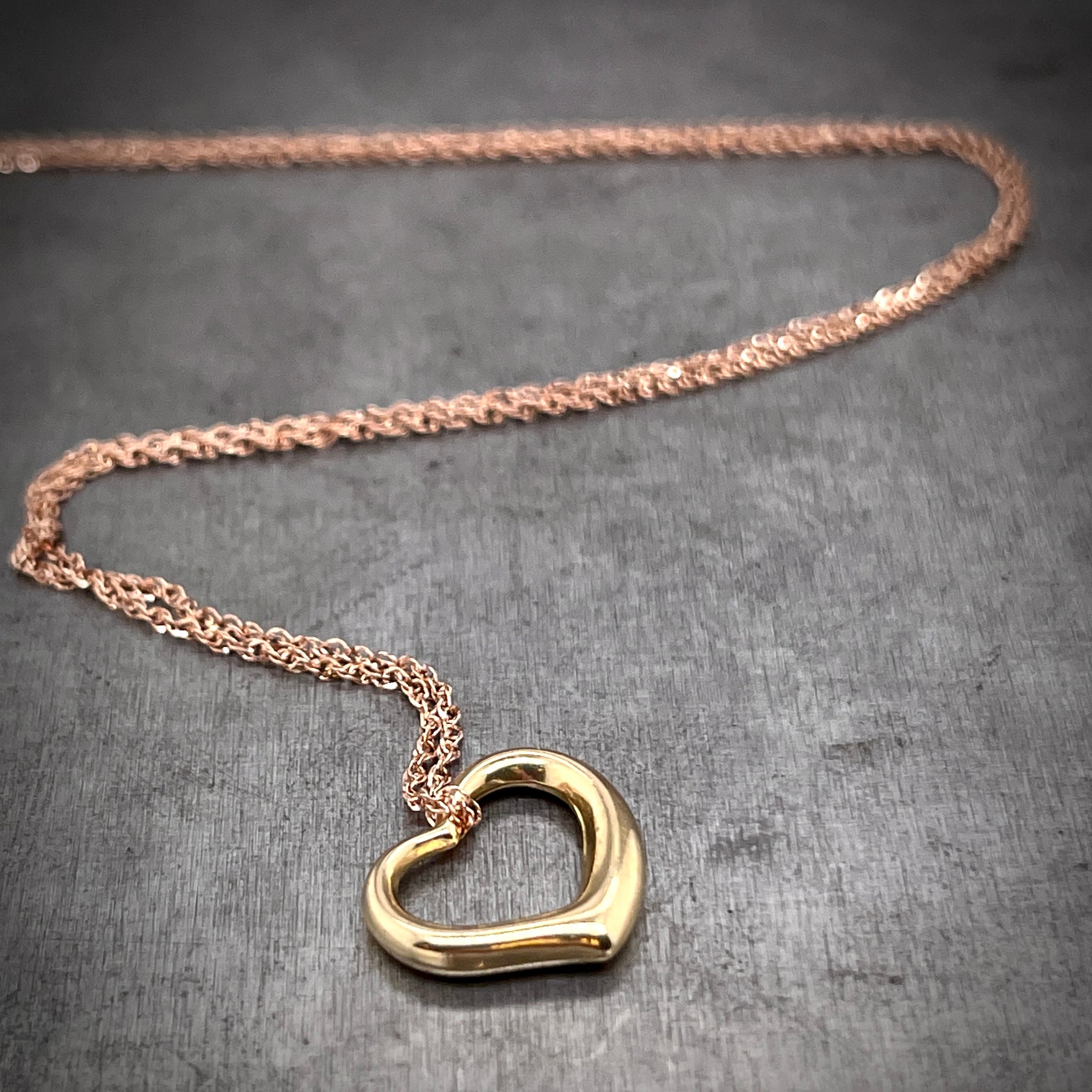 Yellow heart pendant and rose gold chain features laying down with the chain twisting in the background.